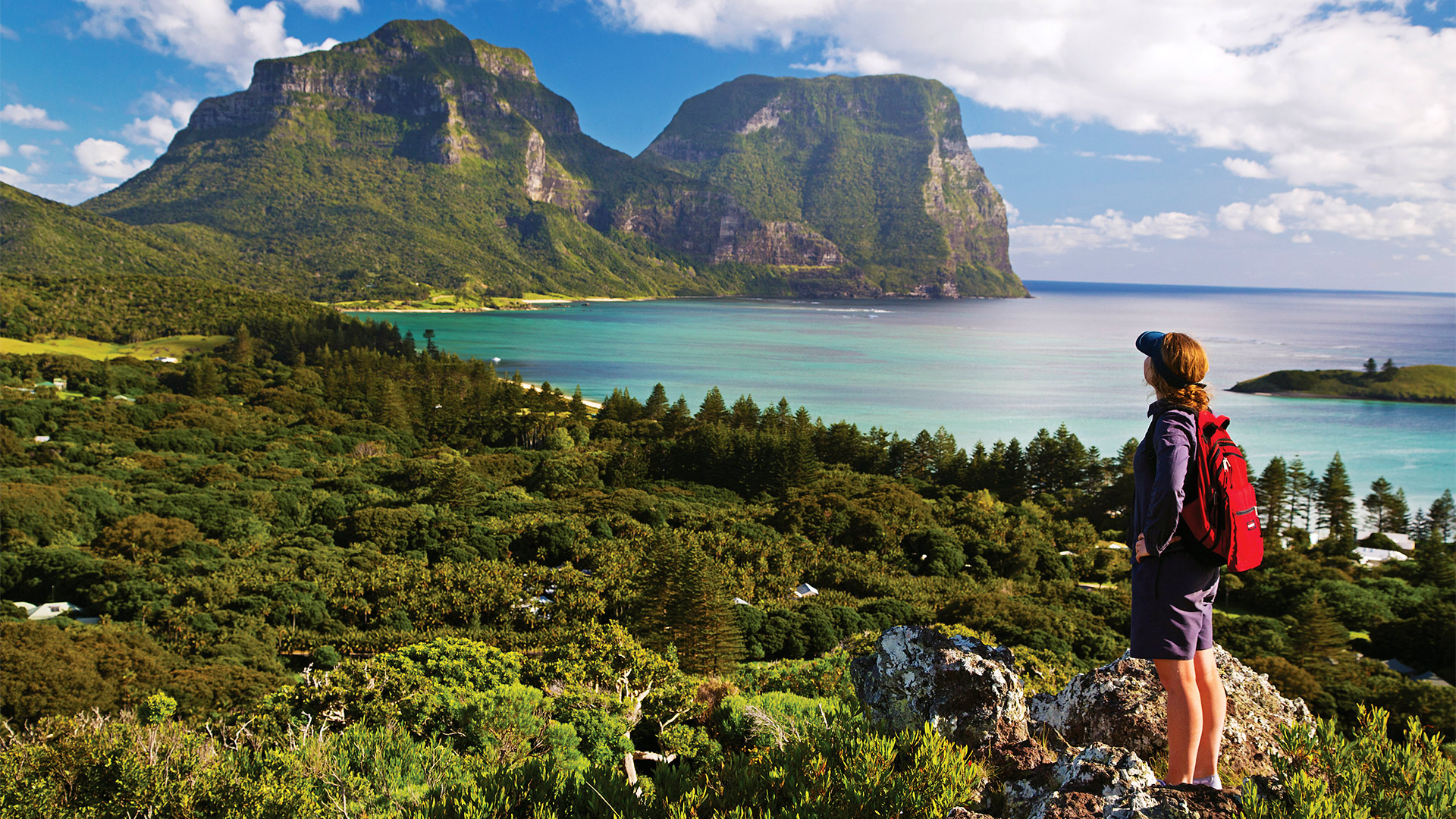 Female hiker looks across mountains and sea in Australia
