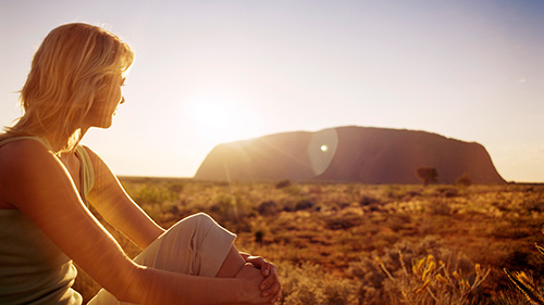 Woman looking towards Ayres Rock in Australia