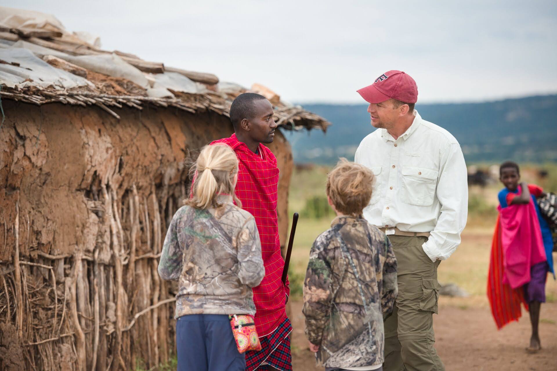Maasai man talks with a father and children in Kenyan village